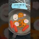 お弁当のおかずの赤ウィンナーとトッピングのなるとと型抜きにんじんを茹で中